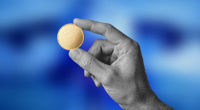 A hand holding a gold coin against a blue background