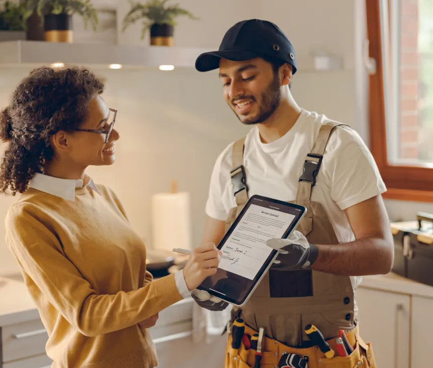 A service technician showing a tablet to a customer in her kitchen