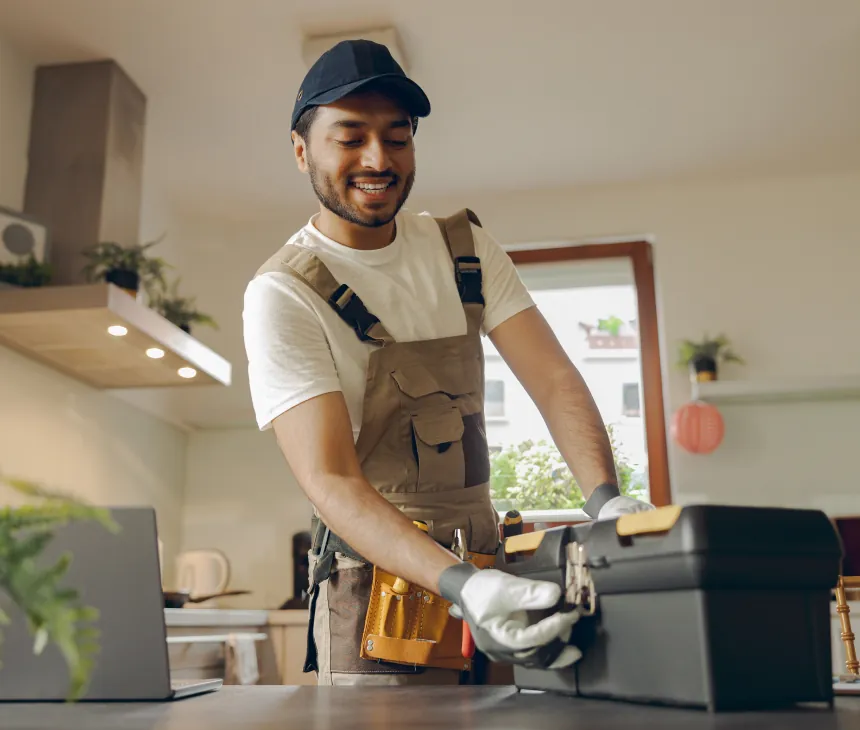 A technician servicing equipment in a kitchen with a laptop open beside him