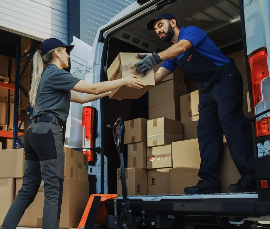 A courier loading parcels into the back of a delivery van