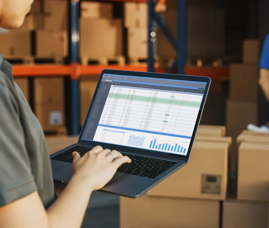 Hands working on a laptop showing a shipment spreadsheet