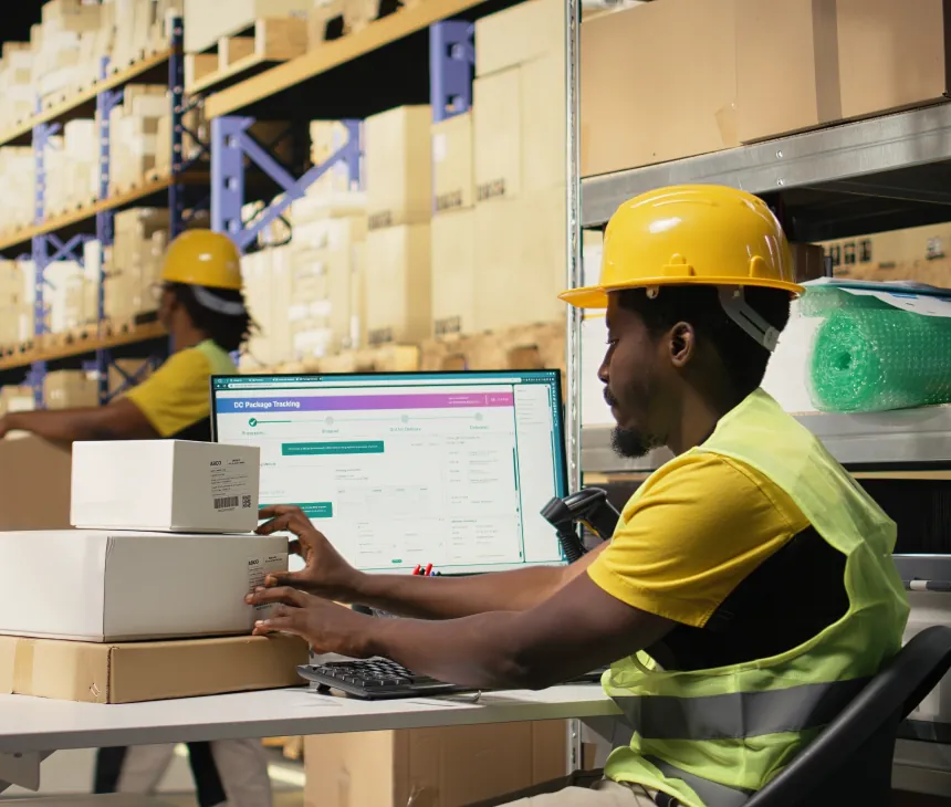 A warehouse operative working at a screen beside packed cartons