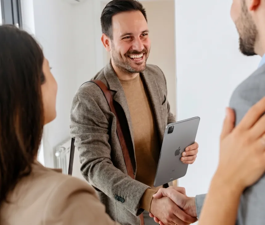 An agent shaking hands with a couple after a viewing