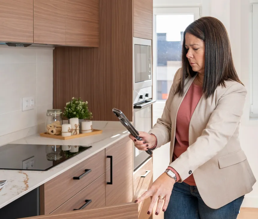 A property manager checking a tablet in an apartment kitchen