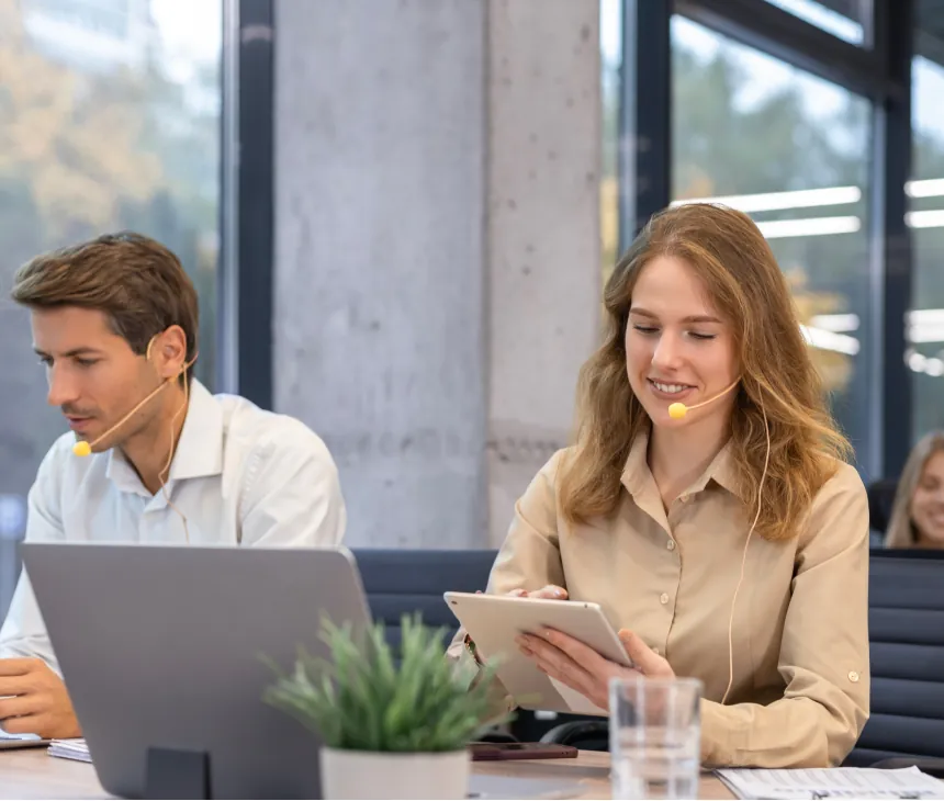 Two colleagues reviewing work on a laptop and tablet in an office