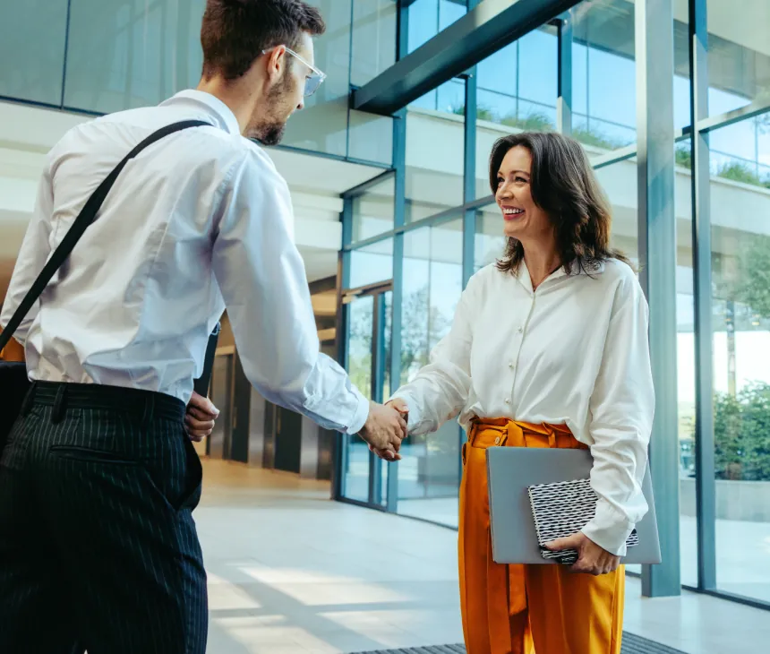 Two colleagues shaking hands in an office atrium