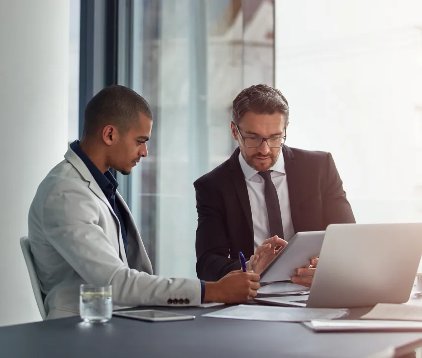 Two advisers reviewing a laptop together at a meeting table